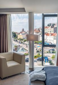 ein Schlafzimmer mit einem Sofa und einem großen Fenster in der Unterkunft Bellevue Superior City Hotel in Šibenik