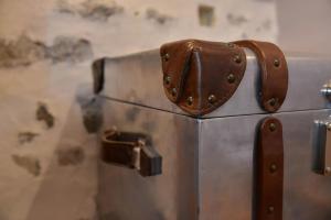 une valise métallique avec une sangle en cuir sur celle-ci, dans l'établissement Hotel Relais De La Cote D'or, à Semur-en-Auxois