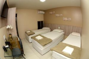 a hospital room with three beds and a television at Hotel Itaparica in Caruaru