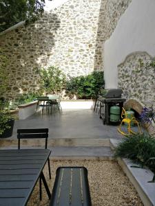 een patio met tafels en stoelen en een grill bij La Maison des Vendangeurs sur Mer in Gruissan