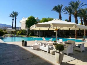 a pool with tables and chairs and an umbrella at Esterin Royal Park Apartments Eilat in Eilat