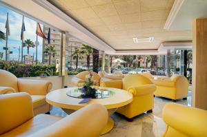 a waiting room with yellow chairs and a table at Hotel Servigroup Venus in Benidorm