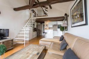 a living room with a couch and a staircase at Luxurious Duplex - Top of Montmartre in Paris