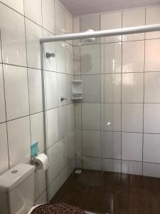 La salle de bains est pourvue de carrelage blanc, de toilettes et d'une douche. dans l'établissement Recanto do Tedo, à Bombinhas