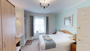 a bedroom with a bed and a bathroom with a sink at The Tudor Guest House in Plymouth