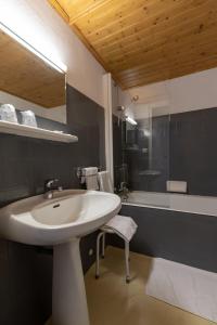 ein Badezimmer mit einem weißen Waschbecken und einer Badewanne in der Unterkunft Hotel Les Esseppes in LʼÉpine