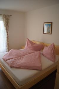 a bed with pink sheets and pillows on it at Schlaferhof - Urlaub am Bauernhof in Fresach