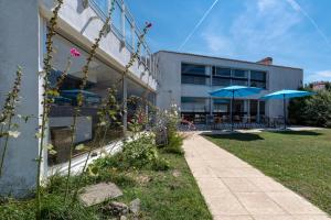 ein Gebäude mit blauen Sonnenschirmen neben einem Bürgersteig in der Unterkunft Hotel Les Esseppes in LʼÉpine