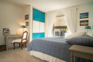 a bedroom with a blue and white bed and a desk at Les Trois Oliviers in Forcalquier