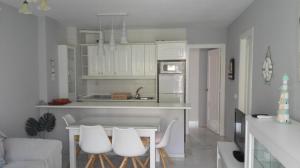 ベナルマデナにあるApartamento en Benalmadena costaの白いキャビネット、テーブルと椅子付きのキッチンが備わります。