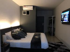 1 dormitorio con 1 cama con almohadas y TV en Hotel Doral Inn en Ibagué