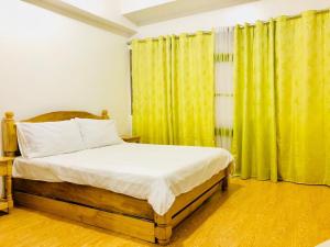 a bedroom with a bed and a yellow curtain at Cedar Peak Condominium in Baguio
