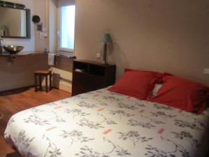 Un dormitorio con una cama con almohadas rojas y una ventana en Festiane, en Decazeville