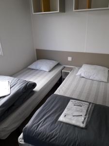Dos camas en una habitación pequeña con 3 estrellas que dice que es lo que dice en Camping Paradis Les Galets de la Molliere, en Cayeux-sur-Mer