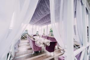 a dining room with white curtains and tables and chairs at Urartu Hotel in Kharkiv