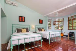 2 Betten in einem Zimmer mit blauen Wänden und Holzböden in der Unterkunft Villa San Ignacio in Alajuela