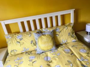a bed with yellow sheets and pillows with a hello pillow at The Sun B&B Rooms in Winforton