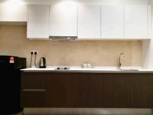a kitchen with white cabinets and a black refrigerator at Mykey Silverscape B-39-07 Melaka City in Melaka