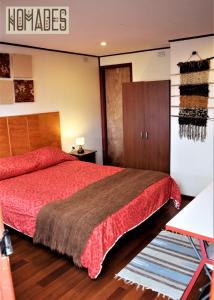1 dormitorio con 1 cama con colcha roja en Nomades Chiloe Apart Hotel, en Castro
