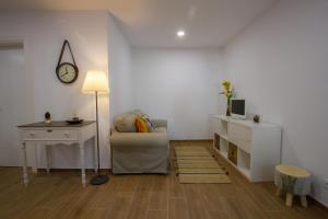 a living room with a chair and a desk and a clock at Casa dos Avós in Villa Nogueira