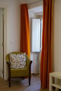a living room with a chair and orange curtains at Casa dos Avós in Villa Nogueira