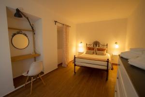 a bedroom with a bed and a mirror and a chair at Casa dos Avós in Villa Nogueira