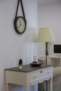 a clock on a wall above a desk with a lamp at Casa dos Avós in Villa Nogueira