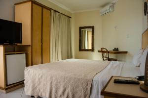 a hotel room with a bed and a television at Via Mar Praia Hotel in Aracaju