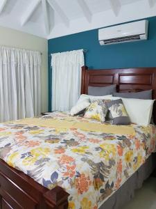 a bedroom with a bed with a floral comforter at Coolshade Villa Mahoe III Ocho Rios in Ocho Rios +29 photos