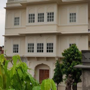 une maison blanche avec un arbre en face dans l'établissement Kishanpura Haveli, à Jaipur