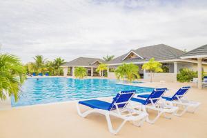 a group of blue and white chairs next to a swimming pool at Coolshade Villa Mahoe III Ocho Rios in Ocho Rios