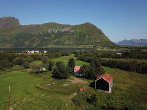 an aerial view of a field with a barn and a mountain at Lofoten Hillside Lodge in Alstad +32 photos