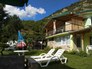 a group of lawn chairs and an umbrella in front of a house at Villa Two Brothers in Ohrid