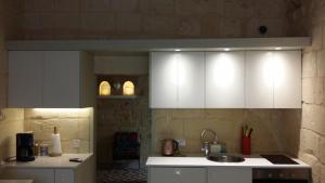 eine Küche mit weißen Schränken und einem Waschbecken in der Unterkunft Magic in the Heart of Old Gozo (First Floor) in Victoria