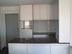 een keuken met witte kasten en een zwart aanrecht bij Malibu Beach in Koksijde +22 foto's