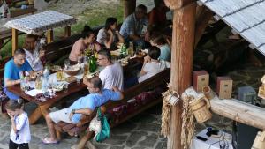 un grupo de personas sentadas en una mesa comiendo en Pensiunea Anca, en Deseşti