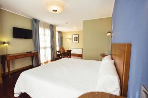 1 dormitorio con cama blanca y escritorio en Hotel El Sella en Cangas de Onís
