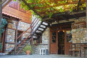 a stone building with a wooden door and a wooden stairs at To Xani in Palaios Panteleimonas