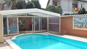 a swimming pool in front of a house with a conservatory at Villa Salvatore in San Leone