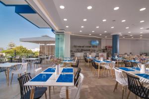 a restaurant with white tables and chairs and a kitchen at Belvedere Village in Agia Pelagia