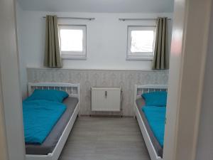 two beds in a small room with blue pillows at An den Linden 31 in Leipzig