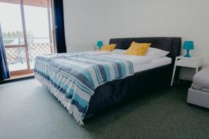 Una cama con una manta azul y blanca y una ventana en Penzión Salamander, en Mlynky 