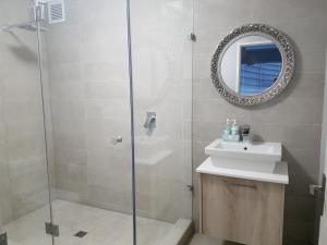 ein Bad mit einer Dusche, einem Waschbecken und einem Spiegel in der Unterkunft WATERS EDGE 103 in Kapstadt