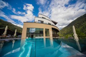 a villa with a swimming pool in the mountains at Heart Hotel Grischuna in Sankt Anton am Arlberg