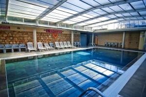 a large swimming pool in a building with chairs at Hotel Servigroup Pueblo Benidorm in Benidorm