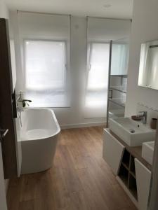 a bathroom with a tub and two sinks and a mirror at le vergoyer in Calais