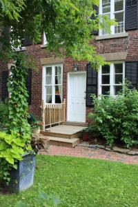 a brick house with a white door and a porch at Auberge Chesley's Inn in Cornwall