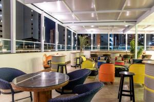 a restaurant with colorful chairs and tables and windows at Hotel Villa Smart in Fortaleza