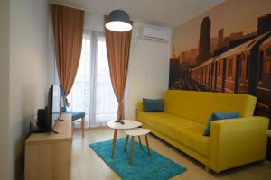 een woonkamer met een gele bank en een tafel bij Flatiron Apartments Skopje in Skopje