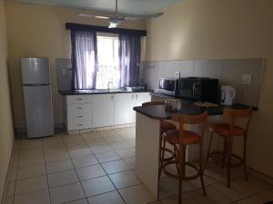 eine Küche mit einem Kühlschrank und einer Theke mit Stühlen in der Unterkunft Emerald Bed&Breakfast in Windhoek
